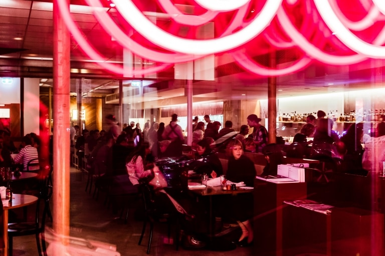 Lampu neon yang terang dan pengunjung memenuhi Supernormal, Melbourne © Trader House Restaurants, Nikki To