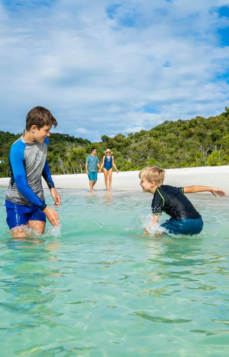 Dua anak bermain-main di air di Whitehaven Beach di Queensland © Tourism and Events Queensland