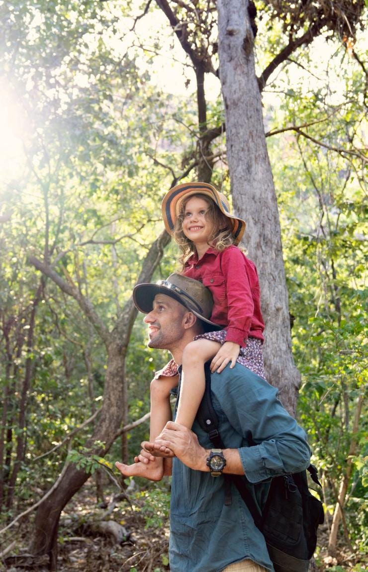 Seorang anak duduk di pundak ayahnya di tengah hutan saat mengikuti tur bersama Offroad Dreaming, Kakadu National Park, Northern Territory © Tourism Australia