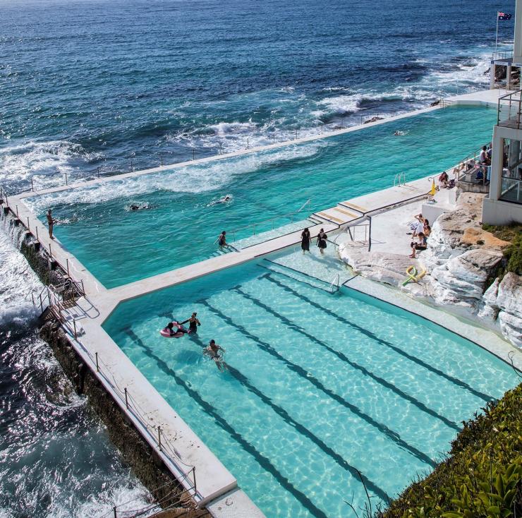 Pemandangan dari udara orang sedang berenang di air berwarna biru muda di Bondi Icebergs, Bondi Beach, Sydney, New South Wales © Destination NSW