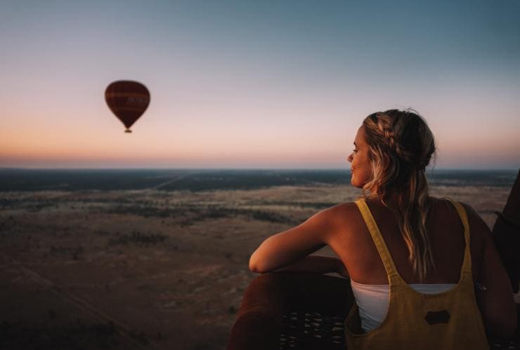Seorang perempuan di atas balon udara memandangi Alice Springs © Tourism NT/Laura Bell 2017