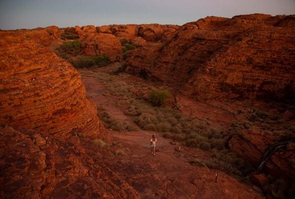 Seorang wanita berjalan melalui bebatuan di Kings Canyon Rim Walk, Kings Canyon, NT © Tourism Australia