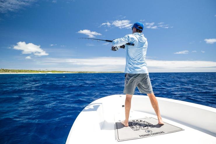 Seorang pria melemparkan kail pancing dari depan perahu di Cocos (Keeling) Islands © Cocos Keeling Islands Tourism Association Seorang pria melemparkan kail pancing dari depan perahu di Cocos (Keeling) Islands © Cocos Keeling Islands Tourism Association