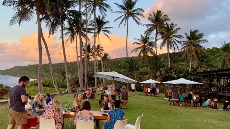 Para pengunjung menikmati makanan dan minuman di bawah pepohonan palem di Rumah Tinggi, Christmas Island © Christmas Island Tourism Association Para pengunjung menikmati makanan dan minuman di bawah pepohonan palem di Rumah Tinggi, Christmas Island © Christmas Island Tourism Association