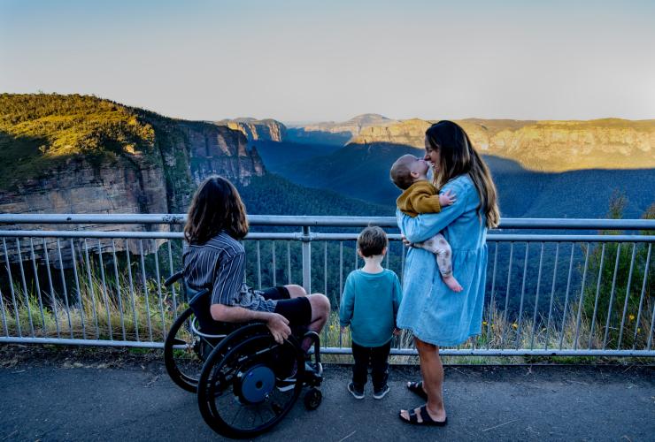Uomo su una sedia a rotelle con la sua famiglia che ammirano le viste delle Blue Mountains, New South Wales © Tourism Australia