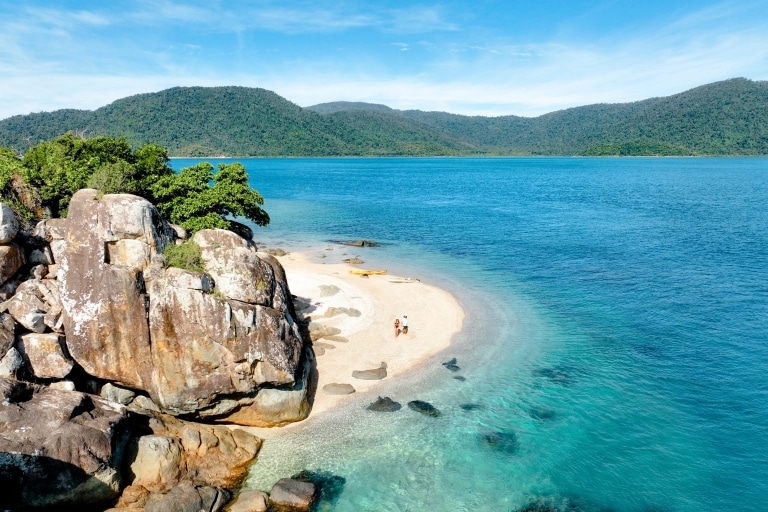 Vista aerea di una coppia che passeggia lungo una spiaggia durante un tour con Salty Dog Adventure nelle Whitsunday, Queensland © Tourism and Events Queensland