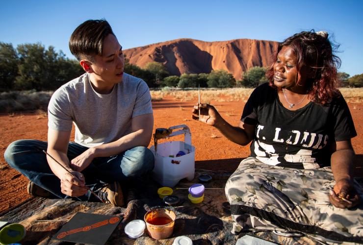 Turista che impara la tecnica di pittura a puntini assieme ad un artista aborigeno di Maruku Arts di Uluru - Kata Tjuta National Park, Northern Territory © Tourism Northern Territory/Archie Sartracom
