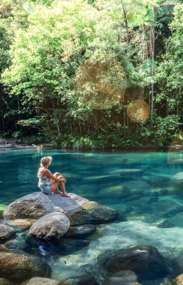 Donna seduta sulla roccia accanto a una piscina naturale di Mossman Gorge © Tourism and Events Queensland