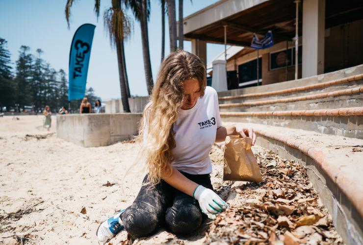 Signora che raccoglie i rifiuti durante la pulizia della spiaggia a Byron Bay © Take 3 for the Sea