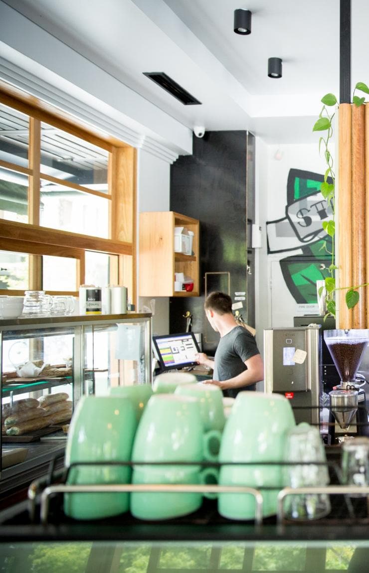 オーストラリア首都特別地域、キャンベラ、コーヒーマシン越しに望むザ・カッピング・ルームの店内 © www.seandaveyphotographer.com