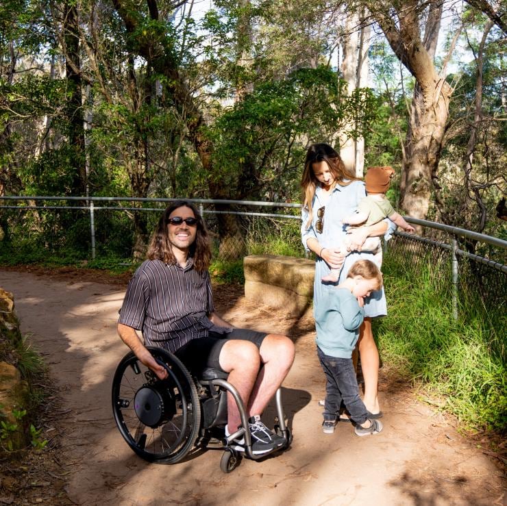 ニュー・サウス・ウェールズ州、ブルー・マウンテンズでトレイルを行く車椅子の男性とその家族 © Tourism Australia