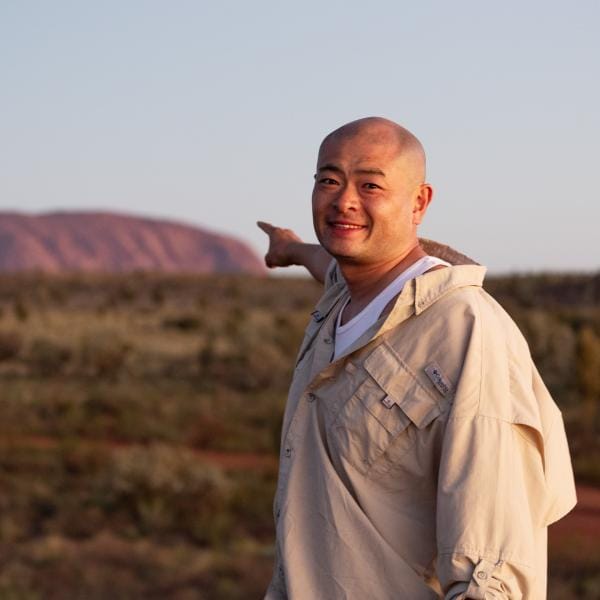 ノーザンテリトリー、ウルル - カタ・ジュタ国立公園、赤い巨大な岩を指す男性  © Tourism Australia