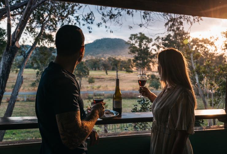 ケリーのトマラップス酪農場で夕日を見ながらドリンクを楽しむカップル © Tourism and Events Queensland/Jesse Lindemann
