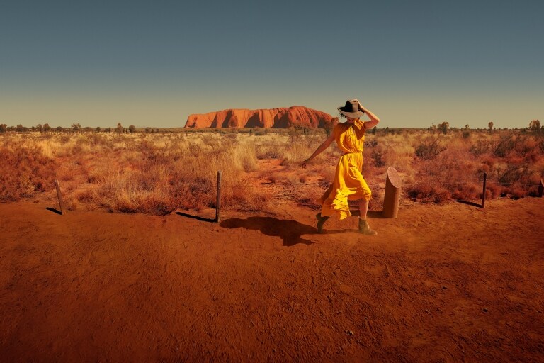 ノーザンテリトリーのウルル ー カタ・ジュタ国立公園のウルルのふもとを歩く女性 © Tourism Australia