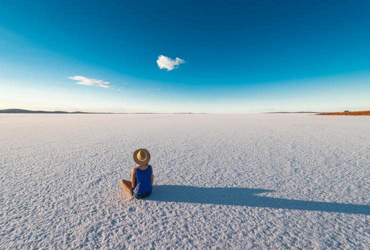 南オーストラリア州でゲイドナー湖の塩原に座っている帽子をかぶった女性 © South Australian Tourism Commission