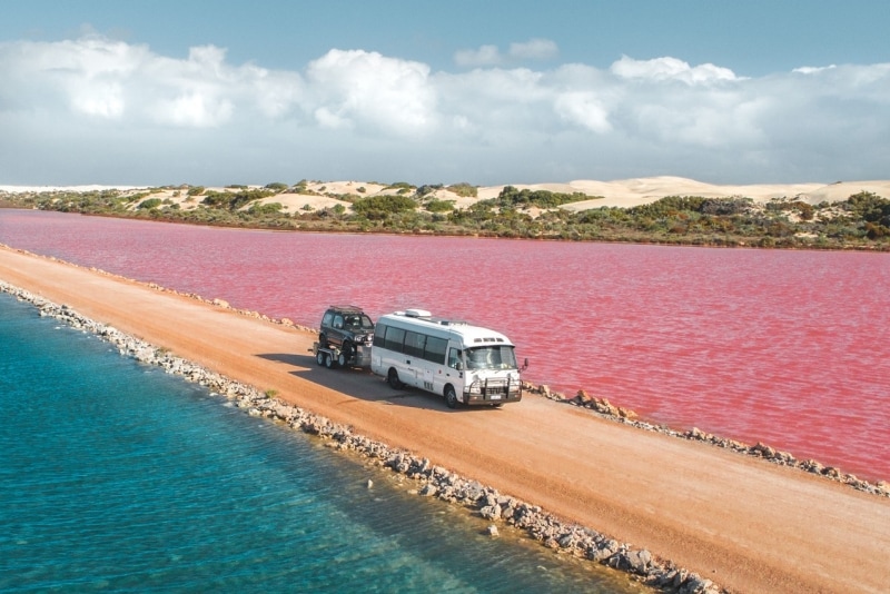 Một chiếc xe van đang chạy trên con đường đất giữa Hồ MacDonnell hồng rực và Hồ Green Lake tại Bán đảo Eyre, Tiểu bang Nam Úc © Jaxon Foale
