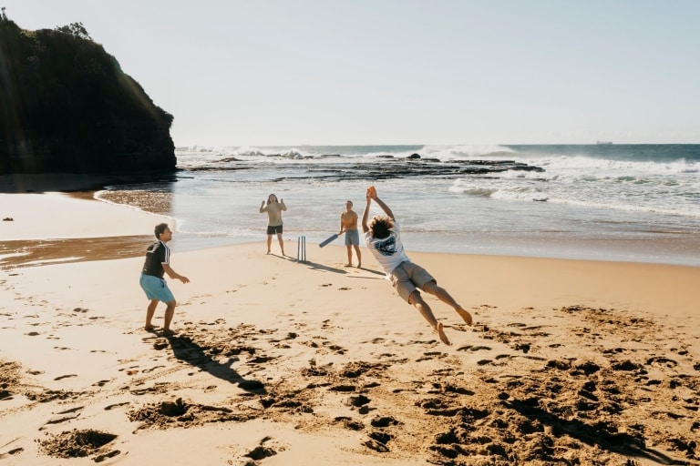 Một nhóm bạn đang chơi bóng gậy trên bãi cát tại Bãi biển Coledale, Vùng Thirroul, Tiểu bang New South Wales © Destination NSW 