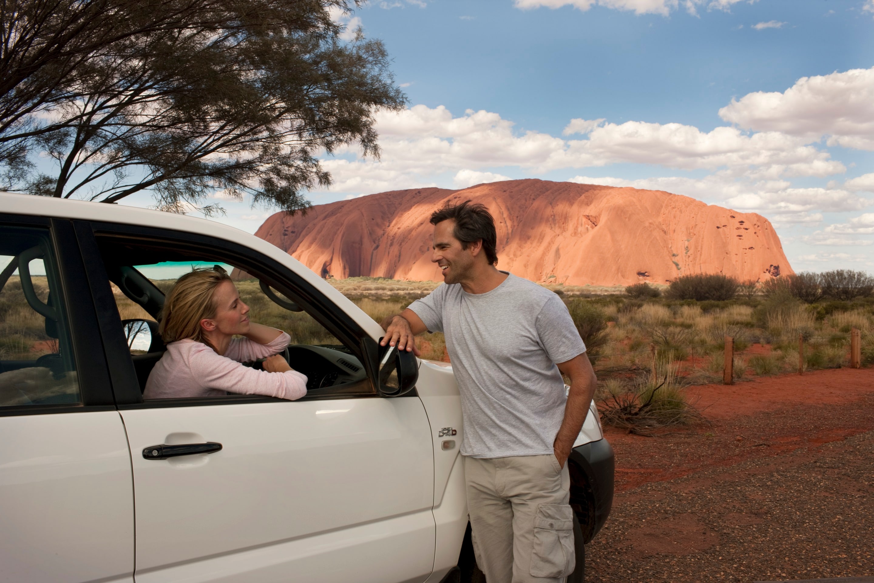 Couple in car parked next to Uluṟu © Tourism Australia