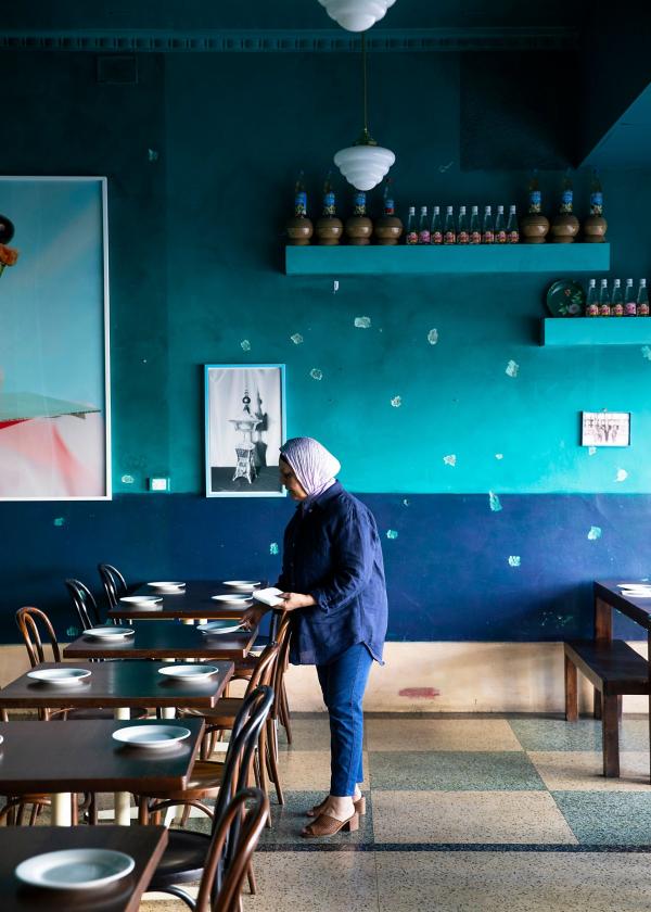 Woman setting tables in a blue interior at Parwana Afghan Kitchen, Adelaide, South Australia © Josie Withers