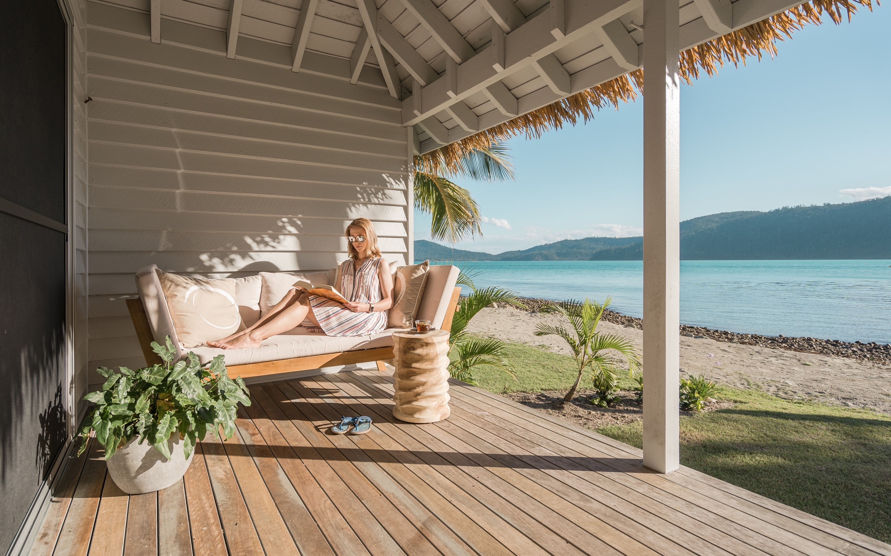 Woman reads book on balcony by ocean at Elysian Retreat © Elysian Retreat/Nathan White