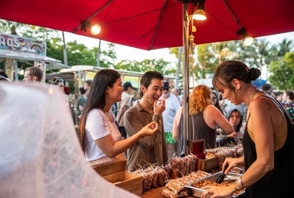 Couple tasting food from a stall at the Mindil Beach Sunset Markets, Darwin, Northern Territory © Tourism NT/Helen Orr