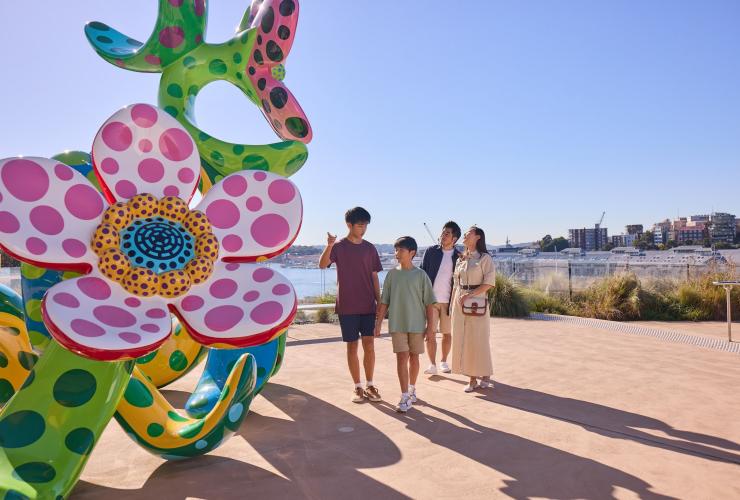 A family outside admiring a large sculpture of spotted flowers at the Art Gallery of New South Wales, Sydney, New South Wales © Tourism Australia