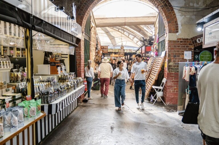 Couple strolling through Fremantle Markets past food stalls, in Fremantle, Western Australia © Tourism Australia