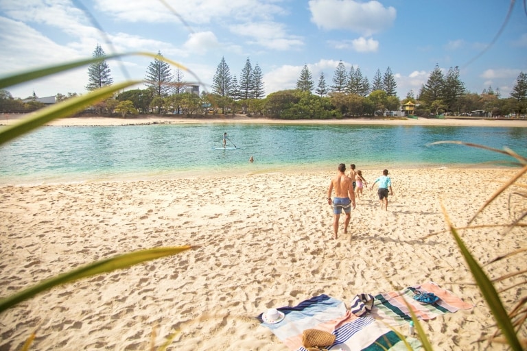 Một gia đình đang chạy trên bãi cát vàng hướng về phía làn nước xanh ngọc, Lạch Tallebudgera, Thành phố Gold Coast, Tiểu bang Queensland © Destination Gold Coast