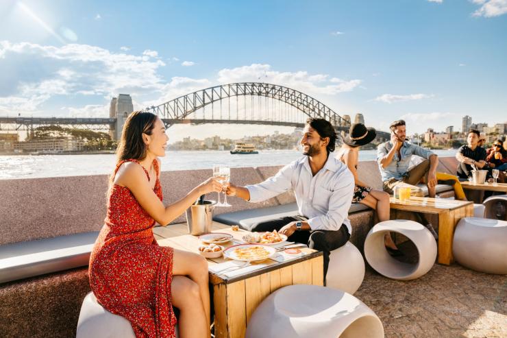 新南威尔士州,一位男士和一位女士在悉尼歌剧院酒吧享用气泡酒和美食并欣赏悉尼海港大桥的景色 © 新南威尔士州旅游局版权所有 新南威尔士州,一位男士和一位女士在悉尼歌剧院酒吧享用气泡酒和美食并欣赏悉尼海港大桥的景色 © 新南威尔士州旅游局版权所有