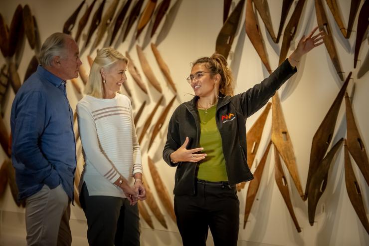 新南威尔士州,悉尼,一对情侣在参观“最早的澳大利亚人展馆”,导游指着墙上的木制文物为他们解说 © 澳大利亚旅游局版权所有 新南威尔士州,悉尼,一对情侣在参观“最早的澳大利亚人展馆”,导游指着墙上的木制文物为他们解说 © 澳大利亚旅游局版权所有