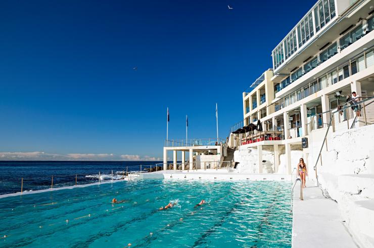 新南威尔士州,邦迪,人们在邦迪冰山泳池的碧水中游泳,左侧是海洋,右侧是亮白色的邦迪冰山俱乐部建筑 © 新南威尔士州旅游局版权所有 新南威尔士州,邦迪,人们在邦迪冰山泳池的碧水中游泳,左侧是海洋,右侧是亮白色的邦迪冰山俱乐部建筑 © 新南威尔士州旅游局版权所有