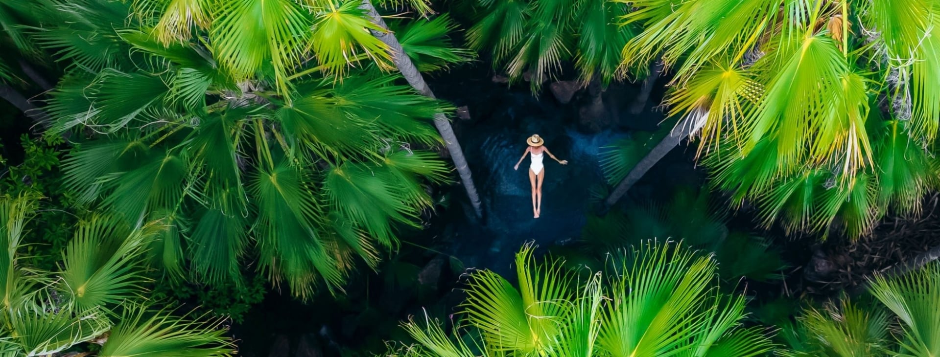 女士在西澳州金伯利的西庇太泉棕櫚樹環繞的環境中享受溫泉（從高空俯瞰拍攝）©澳洲旅遊局