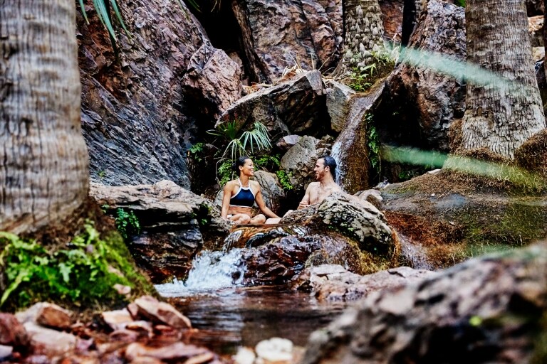 情侶在西澳州（Western Australia）埃爾奎斯特荒野公園（El Questro Wilderness Park）西庇太泉（Zebedee Springs）的天然泉水和茂密綠林間放鬆身心©西澳州旅遊局