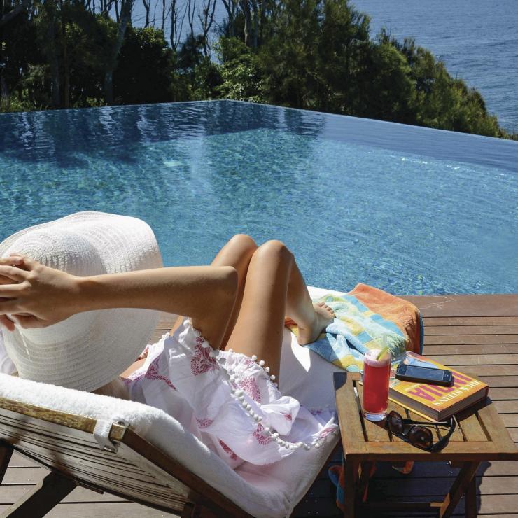 一個女人愜意地坐在南部海岸莫里莫科海灘上的海濱班尼斯特酒店無邊際海景泳池旁。©班尼斯特酒店