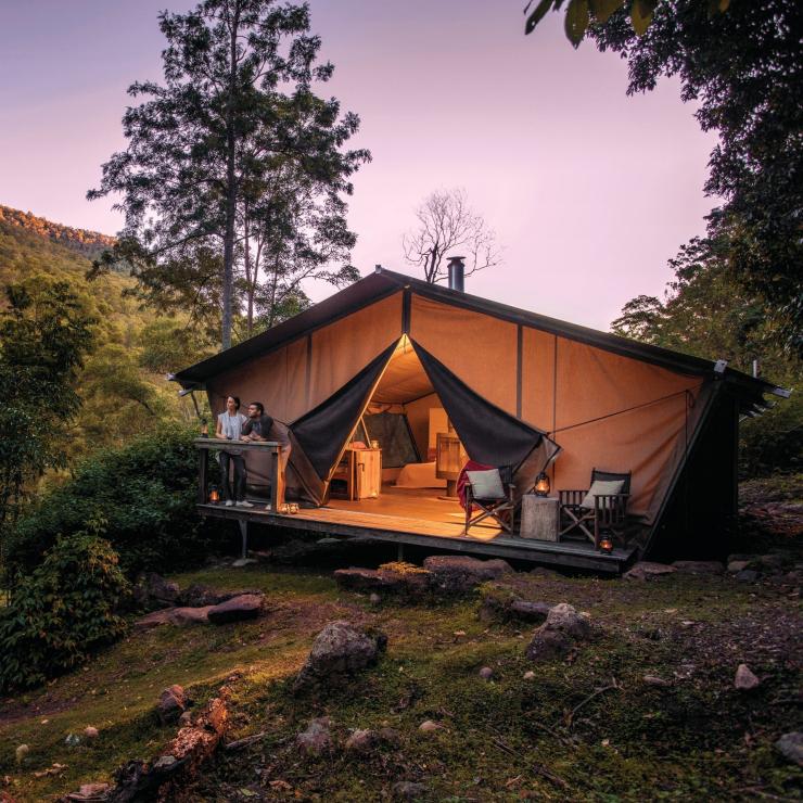 情侶站在夜幕荒野露營地的豪華野營帳篷露台©夜幕荒野露營地