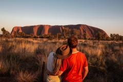 Couple watching sunrise at Uluru © Tourism Australia/Nicholas Kavo