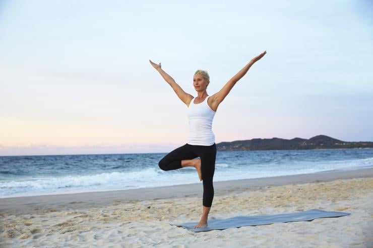 Woman practising yoga at Belongil Beach in Byron Bay © Tourism Australia