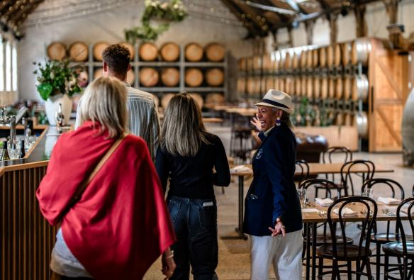 Ein freundlicher, lächelnder Reiseleiter führt eine Gruppe von Personen durch den Fasskeller eines Weinguts, Epic Taste Experiences, Geelong and The Bellarine, Victoria © Epic Taste Experiences