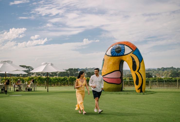 Ein Paar spaziert durch einen Garten mit einer bunten Skulptur, Pt Leo Estate, Mornington Peninsula, Victoria © Visit Victoria