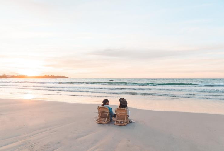 Ein Paar sitzt bei Sonnenuntergang an einem leeren Strand in Robe, Limestone Coast, Südaustralien © Mish and Kirk