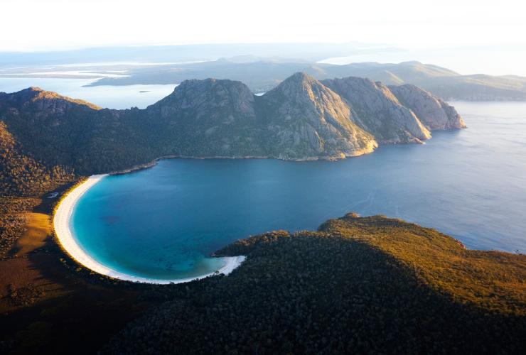 Luftaufnahme von schroffen Bergen und einem weißen Sandstrand, Wineglass Bay, Freycinet National Park, Tasmanien © Lauren Bath
