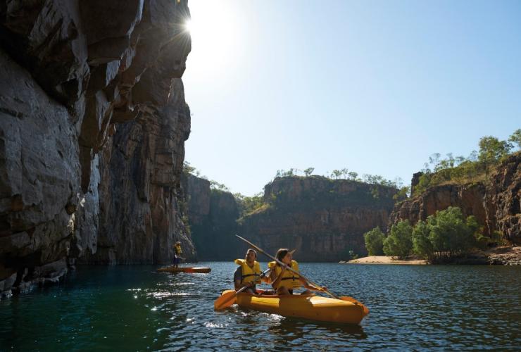 Eine Gruppe von Personen fährt mit Kajaks durch eine Schlucht mit hoch aufragenden Klippen im Nitmiluk National Park, Northern Territory © Tourism NT