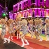 Eine Gruppe von Personen in passenden Paillettenkleidern und mit blonden Lockenperücken überquert beim Sydney Mardi Gras eine mit einem Regenbogen bemalte Straße, Sydney, New South Wales © James Horan/Destination NSW