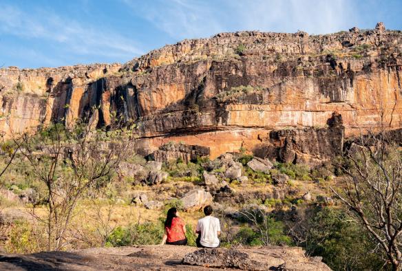 Zwei Freunde sitzen und bewundern die zerklüftete Felslandschaft des Kakadu National Park in der Nähe des Mercure Kakadu Crocodile Hotels, Kakadu, Northern Territory © Tourism NT/Kane Chenoweth