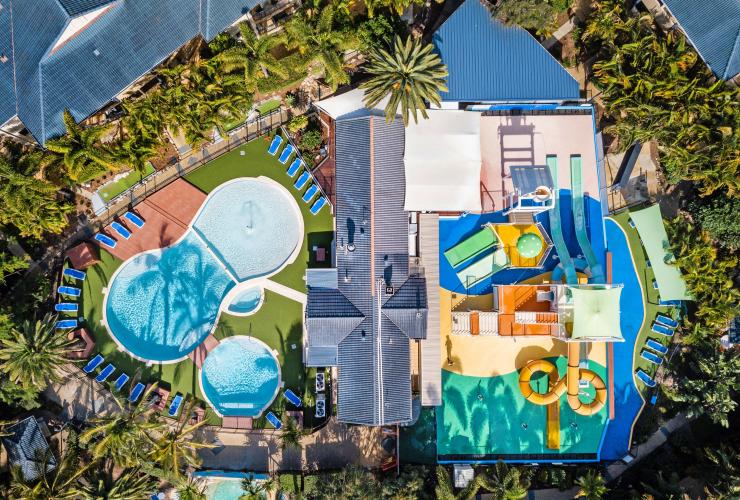 Luftaufnahme über die von Bäumen umgebene Unterkunft mit Pools und einem farbenfrohen Wasserpark im Turtle Beach Resort, Gold Coast, Queensland © Turtle Beach Resort