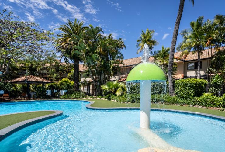 Ein Wasserspiel in einem Pool umgeben von Palmen mit einem Gebäude im Hintergrund im Turtle Beach Resort, Gold Coast, Queensland © Turtle Beach Resort