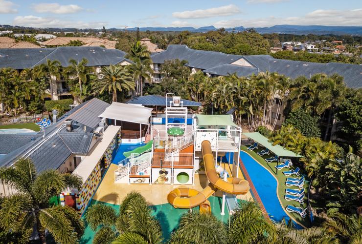 Luftaufnahme über die von Bäumen umgebene Unterkunft mit einem Wasserpark und Wasserrutsche inmitten des Turtle Beach Resort, Gold Coast, Queensland © Turtle Beach Resort