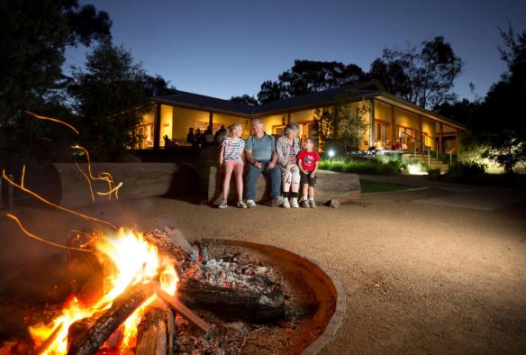 Eine Familie sitzt im Zoofari Lodge und Billabong Camp abends um ein Lagerfeuer, Taronga Western Plains Zoo, Dubbo, New South Wales © Taronga