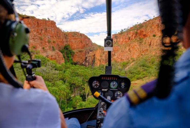 Zwei Personen fliegen in einem Hubschrauber über felsige Schluchten, El Questro Homestead, East Kimberley, Westaustralien © El Questro Homestead