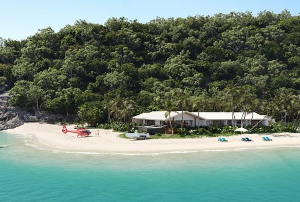 Luftaufnahme eines Gebäudes, das von Regenwald und einer weißen Sandküste umgeben ist, mit einem roten Hubschrauber, der in der Nähe geparkt ist, Pelorus Private Island, Palm Island, Queensland © Pelorus Private Island